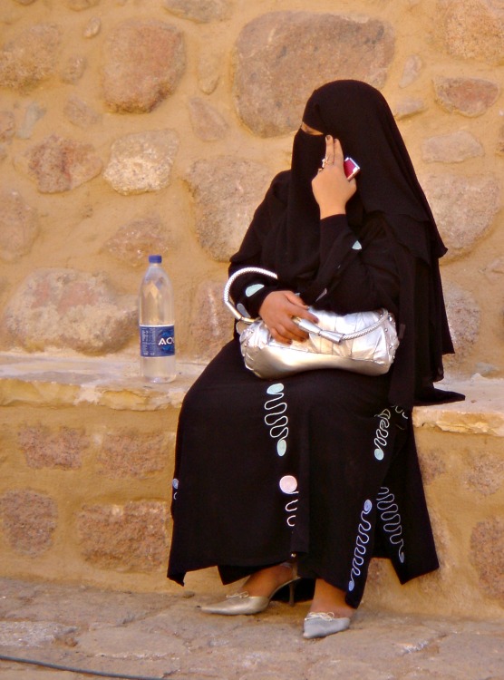 Woman in a burka and high heels, bag and mobile phone